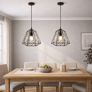 Two black metal pendant lights hang over a wooden dining table set with a bowl of fruit and tableware.