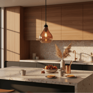 Rose copper pendant light hanging above a kitchen island with a bowl of fruit and coffee cups.
