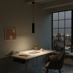 Black cylindrical pendant light illuminating a modern desk setup with a plant and laptop.