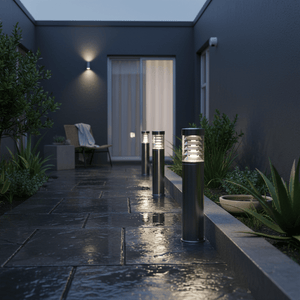 Stainless steel bollard lights illuminate a wet stone pathway with surrounding greenery.