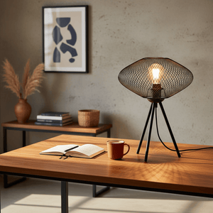 Stylish black mesh table lamp on a wooden desk with a notebook and coffee cup, enhancing modern decor.