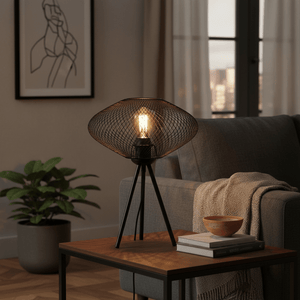 Black mesh table lamp on a wooden side table, with a cozy sofa and plant in the background.
