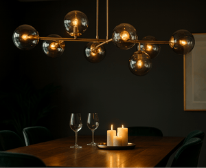 Modern chandelier with glass bulbs in a dimly lit room with a table and candles.