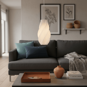 A white 3D printed pendant light hangs above a modern grey sofa with colorful cushions and a coffee table.