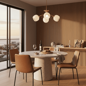 Gold metal chandelier with white glass shades illuminating a modern dining area with a round table.