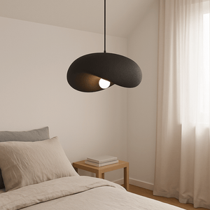 Obsidian Drift 500 Pendant Light hanging above a bed with neutral bedding and a wooden side table.