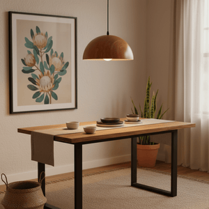 Dome wood grain pendant light hanging above a wooden dining table set with plates and bowls, featuring a plant and artwork