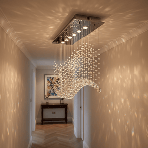 Waverley Chrome Chandelier with crystal detailing suspended in a stylish hallway, casting reflections on the walls.