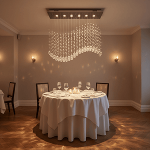 Waverley Chrome Chandelier elegantly suspended above a round dining table set for dinner, casting soft light.