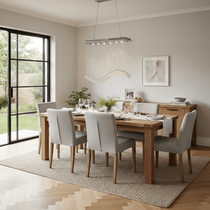 Stylish dining room featuring a Waverley Chrome Chandelier above a wooden table set for dinner.