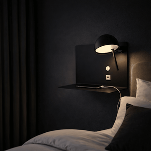 Contemporary black USB wall light mounted beside a bed, illuminating a nightstand with a phone charging.