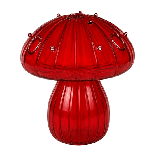 Ruby red glass mushroom vase with ribbed cap, studs and circular cutouts, set against green background