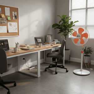 Orange and white ACDC pedestal fan standing in an office corner beside a desk and window blinds