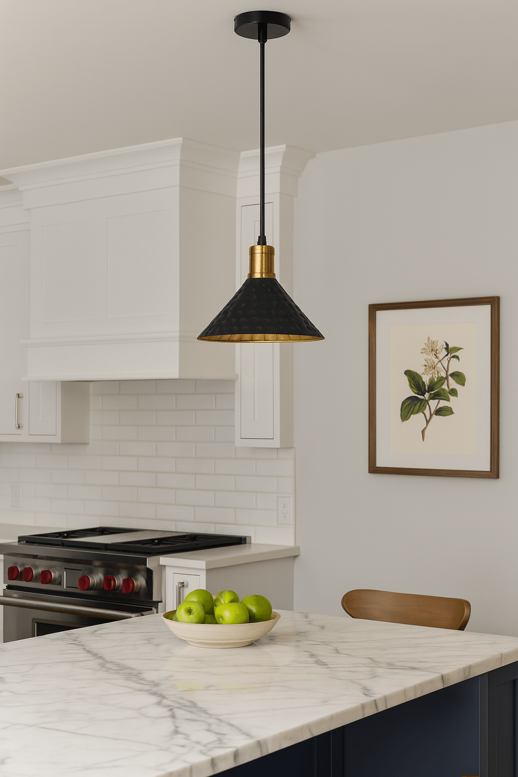 Black iron pendant light with gold accents hanging over a marble kitchen island with green apples.