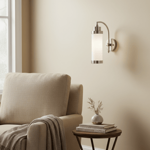 Antique silver Kerala Wall Lamp mounted beside a cozy beige couch, illuminating a warm indoor space.