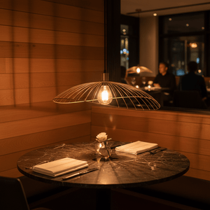 Satin-gold Sensu Solo pendant light hanging over a marble dining table, creating a warm ambiance.