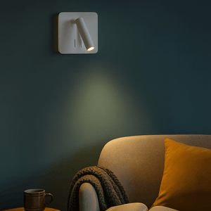 Wall-mounted light fixture casting a warm glow on a cozy living room corner with a book and mug.