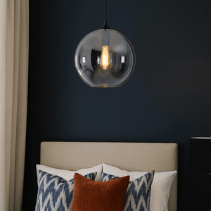 Modern bedroom with a pendant light fixture, bed with patterned pillows, and dark wall.