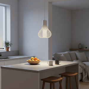 Scandi white pendant light hanging above a kitchen island with a bowl of fruit and two mugs.