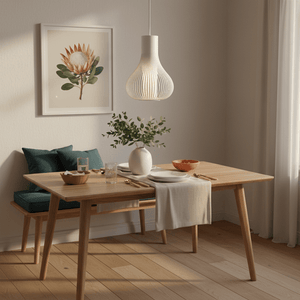 Scandi white pendant light hanging above a wooden dining table set with plates and a vase.