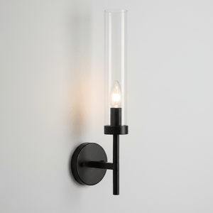 Black metal wall light with clear glass shade mounted on a smooth wall, showcasing a visible lamp.