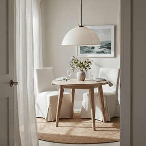 A small dining area featuring a handwoven rattan pendant light above a wooden table with two chairs and decorative elements.
