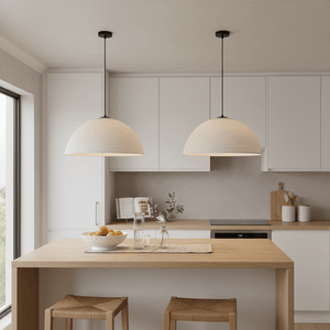 Two Breyten Antique White Rattan Pendant Lights hanging over a wooden kitchen island with a bowl of fruit.