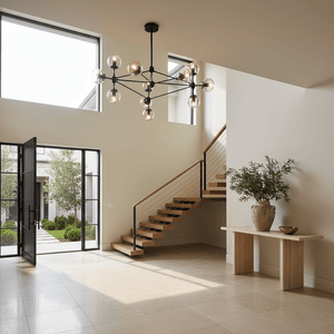 Stylish black and amber chandelier hanging in a modern foyer with a staircase and natural light.