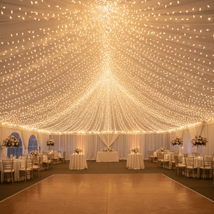 Warm white LED fairy lights draped across a tent ceiling, illuminating a festive dining setup.