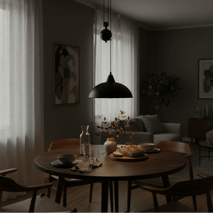 Colchester Black Pulley Pendant Light hanging above a wooden dining table set with plates and a vase.