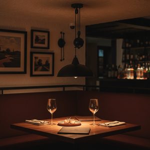 Colchester Black Pulley Pendant Light illuminating a cozy dining table with wine glasses and a dish.