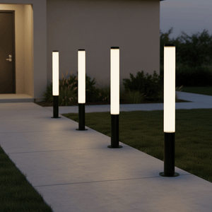 Four black LED bollard lights illuminate a pathway leading to a door, set in a landscaped area.