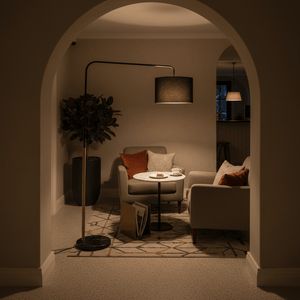 Stylish black and gold floor lamp illuminating a cozy reading nook with armchairs and a coffee table.