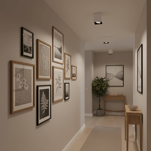 Modern surface mount downlights illuminating a gallery-style wall of framed artwork in a hallway.
