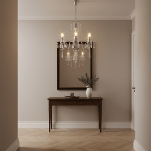 Elegant three-arm crystal chandelier hanging above a wooden console table with a mirror and decorative vase.