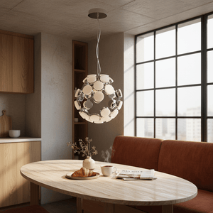 A chrome pendant light with a spherical design hangs above a round wooden table, surrounded by a cozy setting.