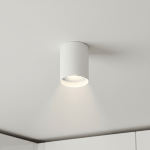 Close-up of a white adjustable surface-mounted GU10 downlight installed on a ceiling, illuminating a kitchen area.