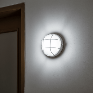 White LED cage bulkhead light mounted on a wall, illuminating the area with a cool-white glow.