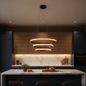 Modern black LED pendant light with crystal rings hanging above a kitchen island, illuminating a marble countertop.