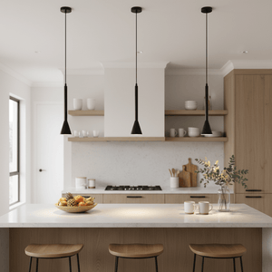 Three black pendant lights hang over a kitchen island with a fruit bowl and wooden stools.