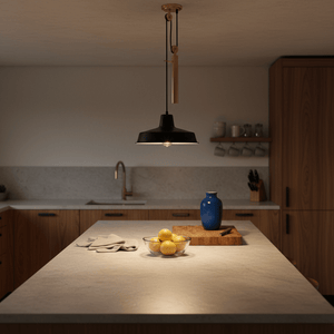 Coleford Black & Brass Pulley Pendant Light illuminating a kitchen island with lemons and a blue vase.