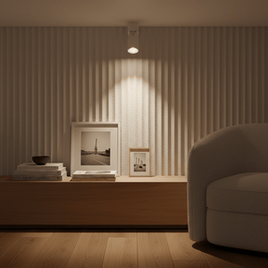 Adjustable surface mount downlight holder illuminating textured wall above a wooden shelf with framed photos.