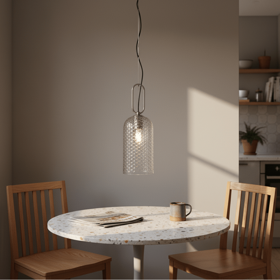 Clear glass pendant light hanging above a round table with wooden chairs, illuminated softly.