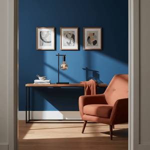 Black E27 table lamp on a wooden console table against a blue wall, with framed art and an orange chair.