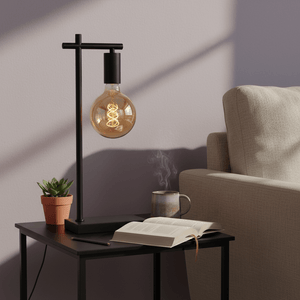Black E27 table lamp on a side table with a book, coffee mug, and potted plant, creating a cozy reading corner.