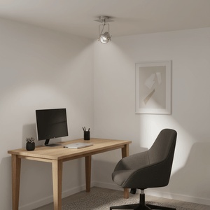 Satin chrome ceiling spotlight illuminating a modern desk setup with a computer and chair.