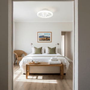 A cozy bedroom featuring a Caledon Flush Mount LED Ceiling Fan, with a bed, decorative pillows, and a woven chair.