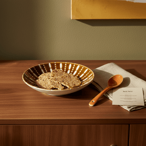 Ceramic flat bowl in burned orange with a sea urchin pattern, holding cookies on a wooden surface with a spoon and napkin.