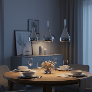 Three polished chrome pendant lights hang above a wooden dining table set with dishes and a floral centerpiece.