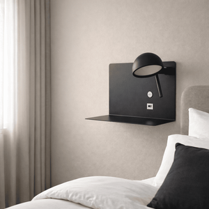 Black USB wall light mounted beside a bed, featuring a sleek design and soft glow.